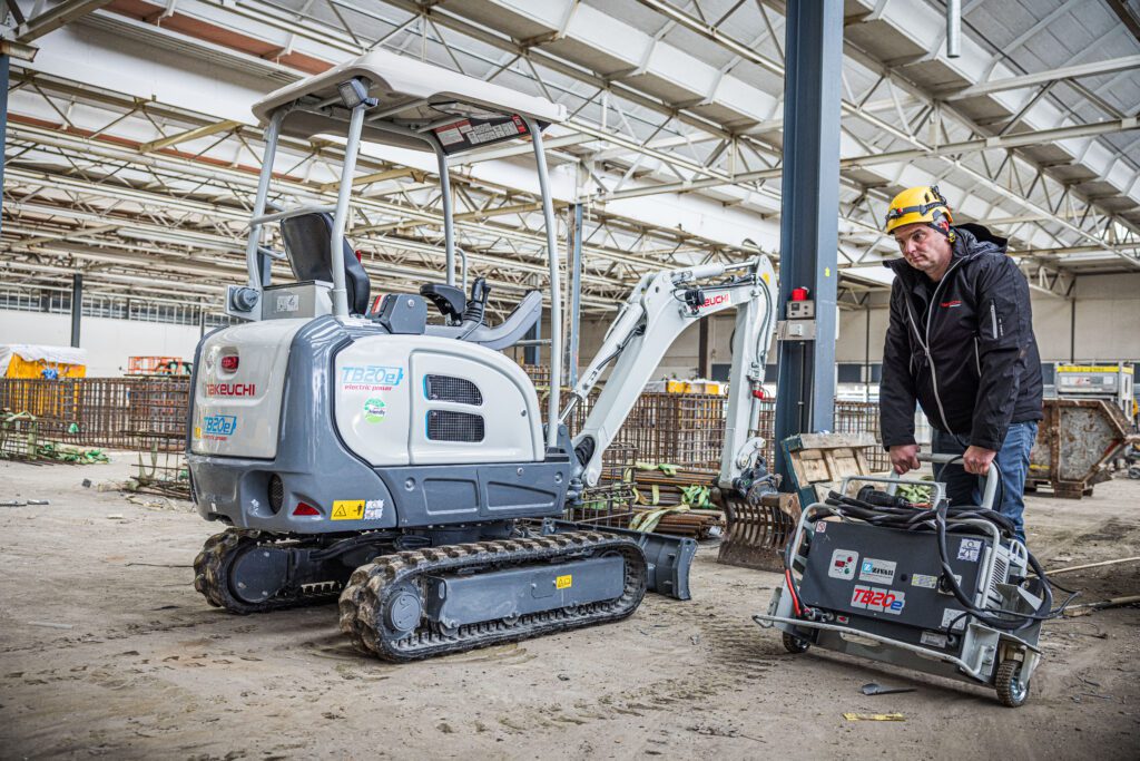 Graafmachinist die het oplaadsysteem gaat aansluiten op de Takeuchi TB20e elektrische minigraver