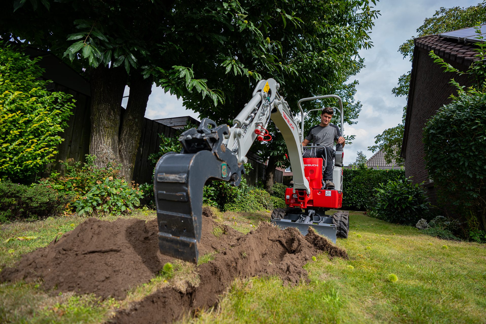 Minigraver in tuin sleuf aan het graven