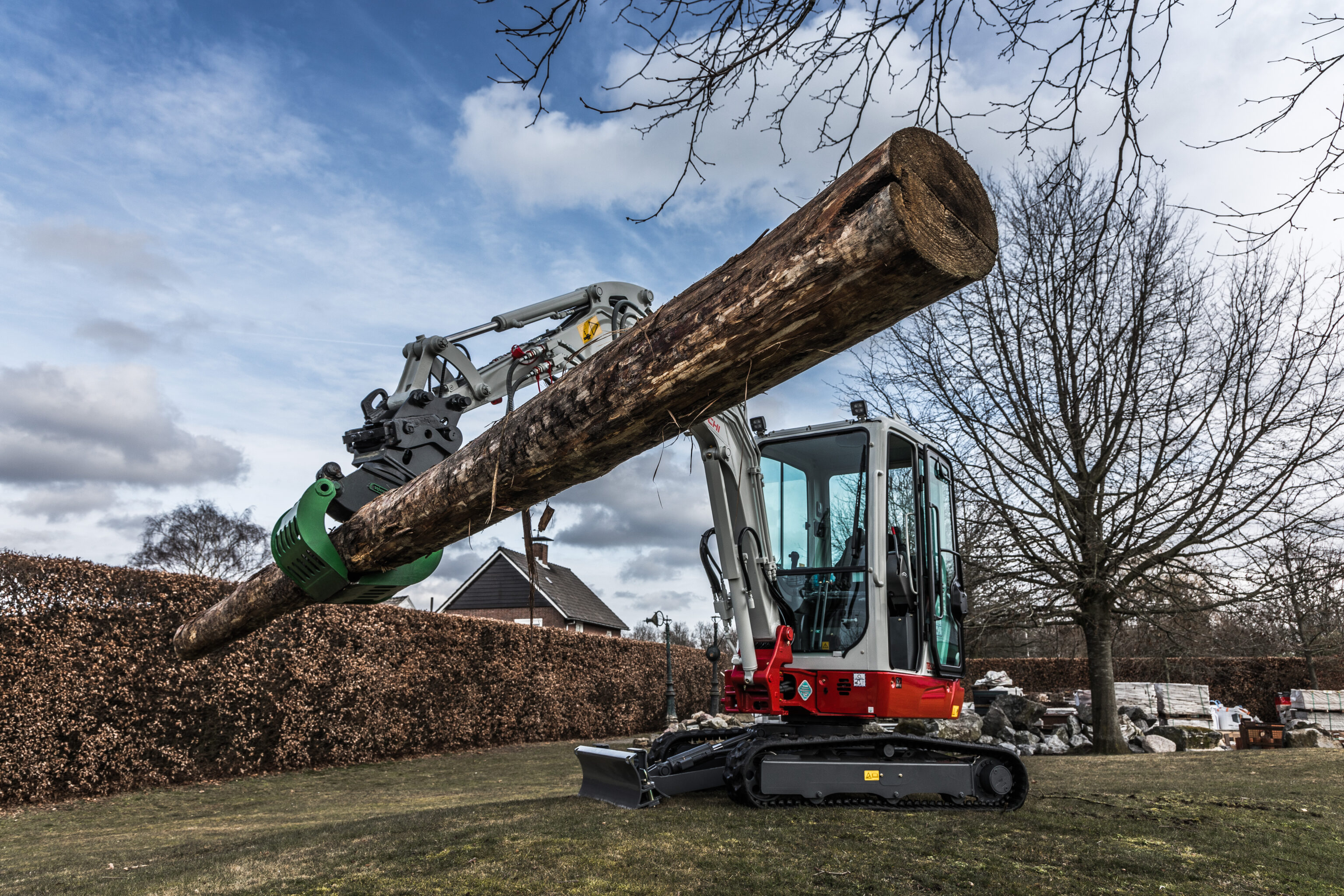 De Takeuchi TB225 tilt een grote boomstam op