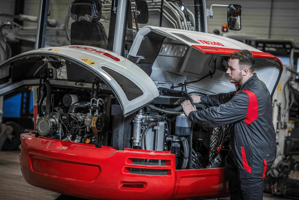 Monteur bij motor van takeuchi bezig