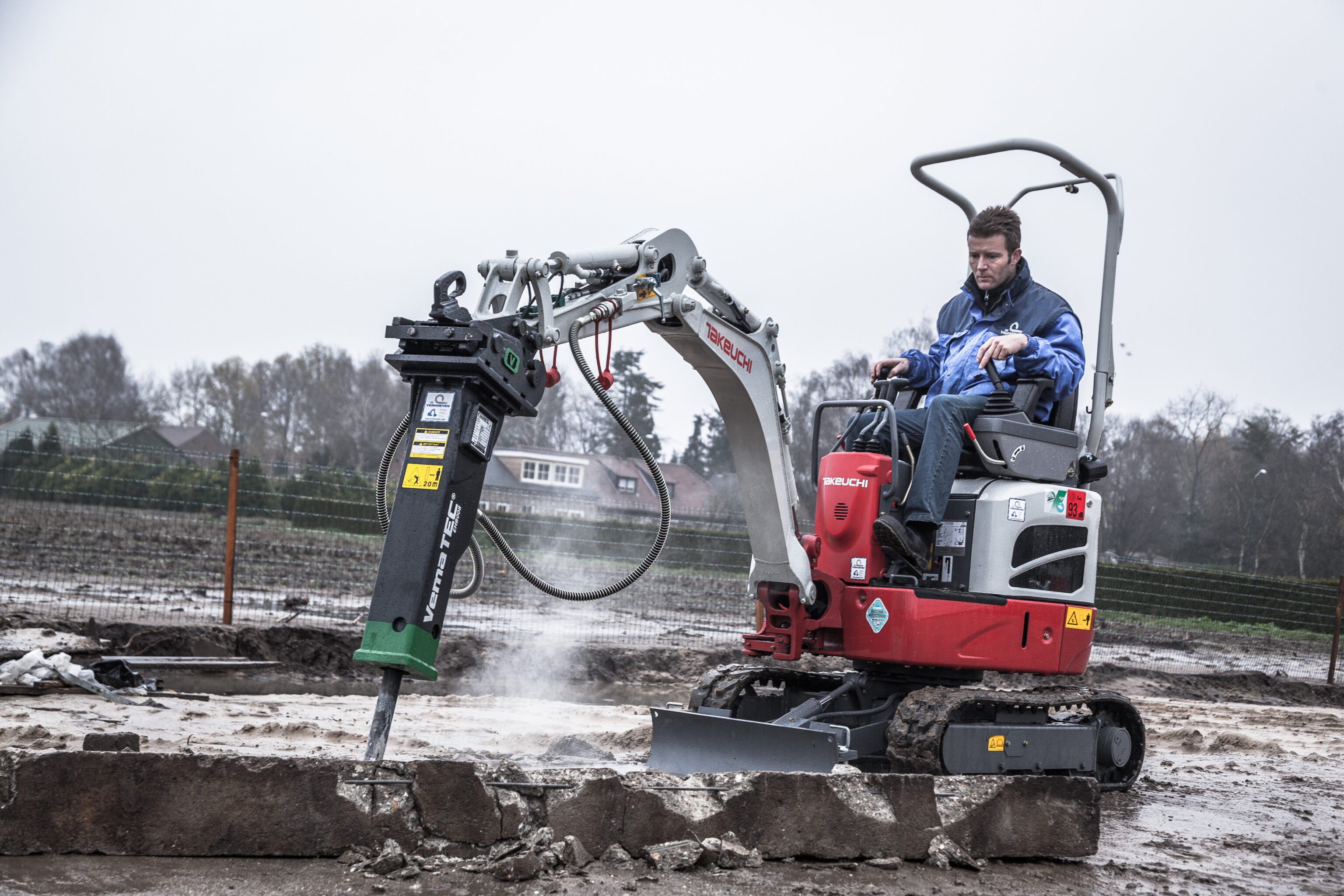 Minigraver op bouw met een sloophamer