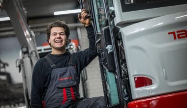 Monteur lachend leunend tegen Takeuchi graafmachine