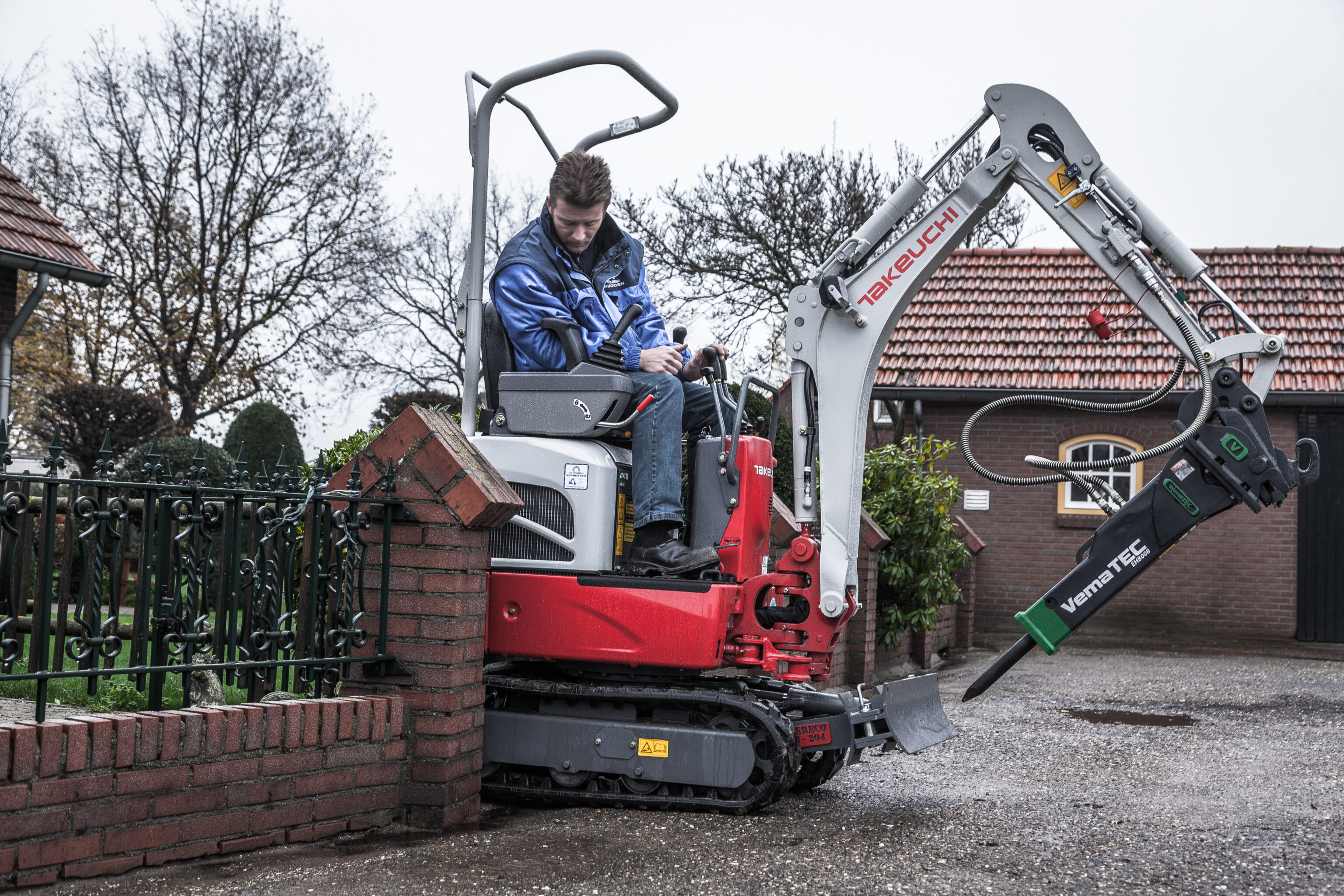 Takeuchi rijdt door smal tuinhekje