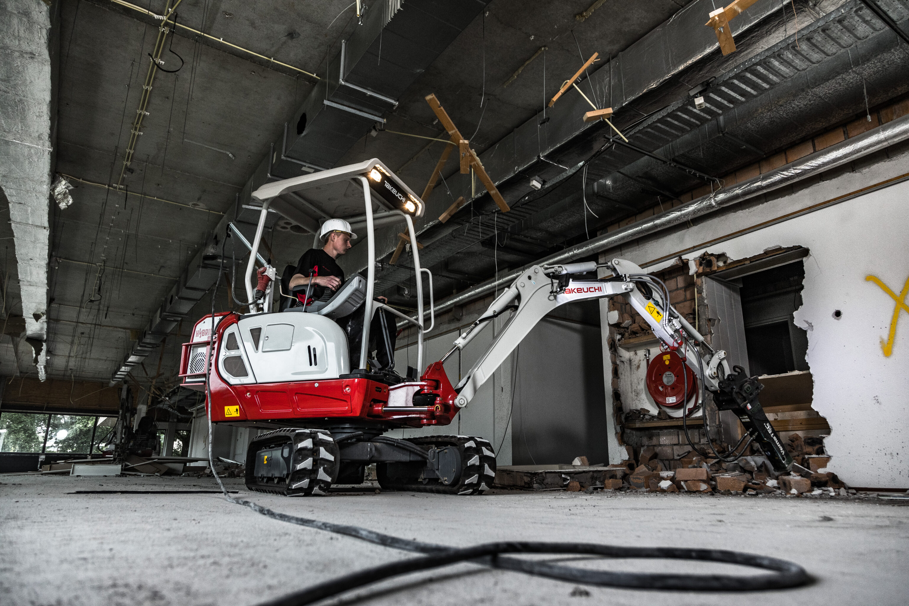 Hybride graafmachine in binnen werkplaats met sloophamer
