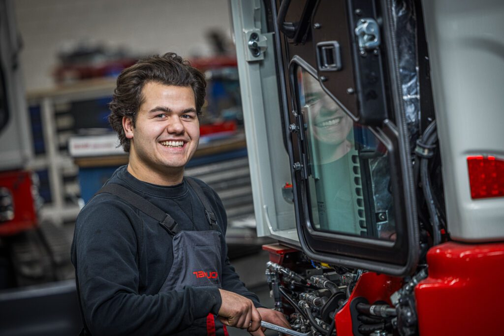 Takeuchi Monteur lachend naar camera