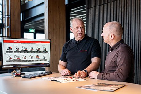 Takeuchi specialist die een klant adviseert welke graafmachine het beste aansluit bij zijn opdrachten