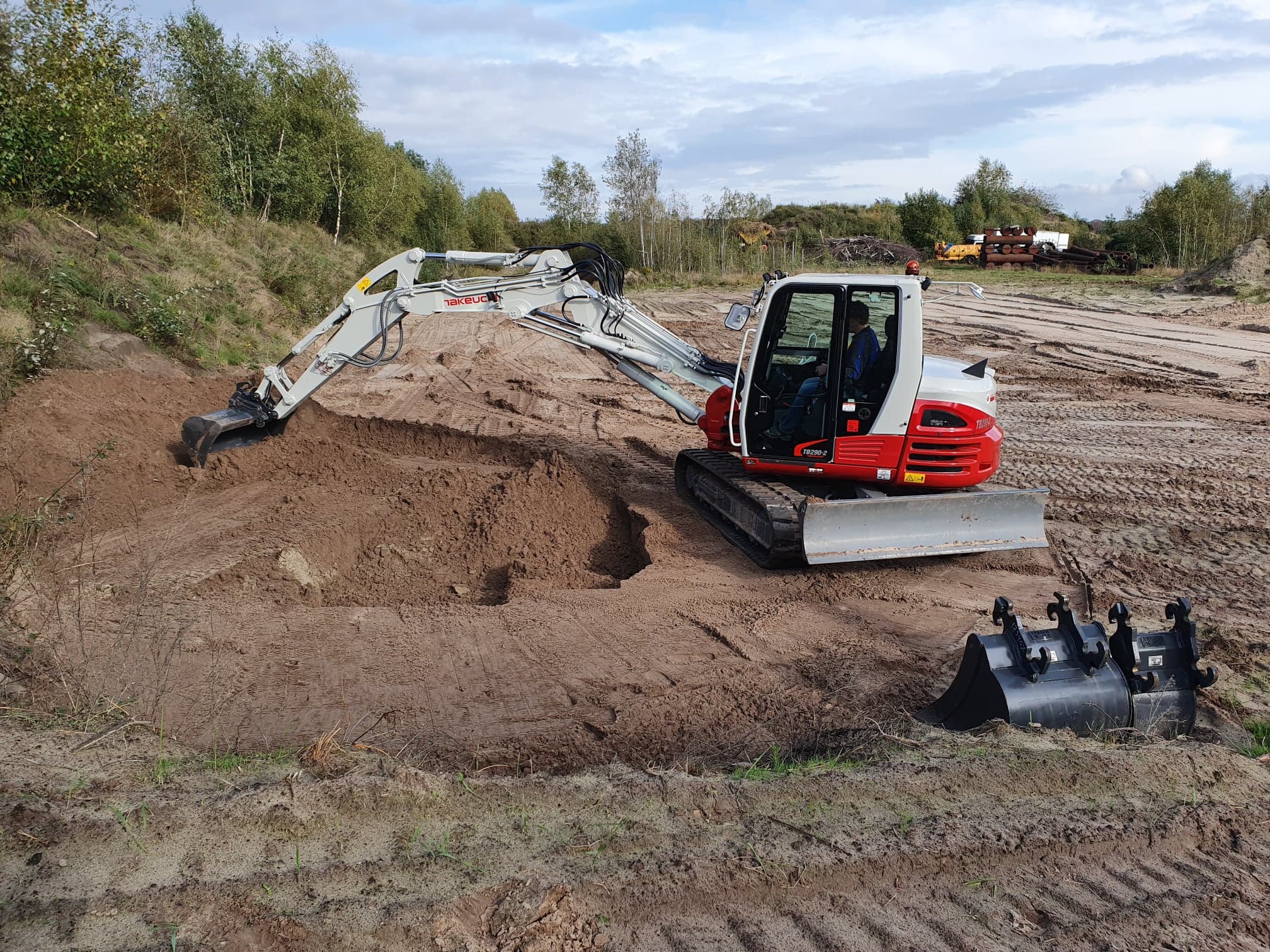 Takeuchi graafmachine die met een slotenbak aan het graven is