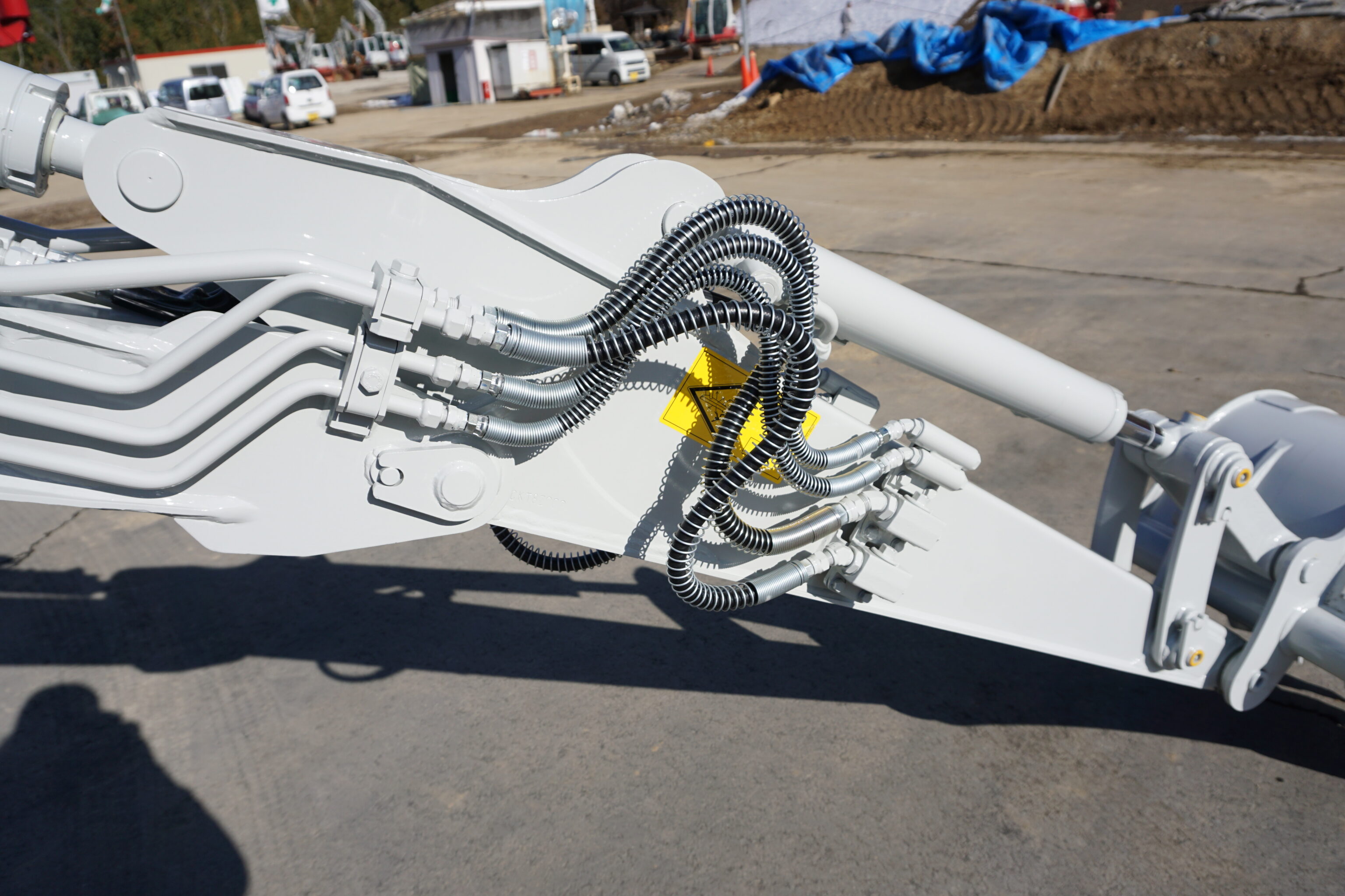 Hydraulische slangen aan de giek van een Takeuchi graafmachine