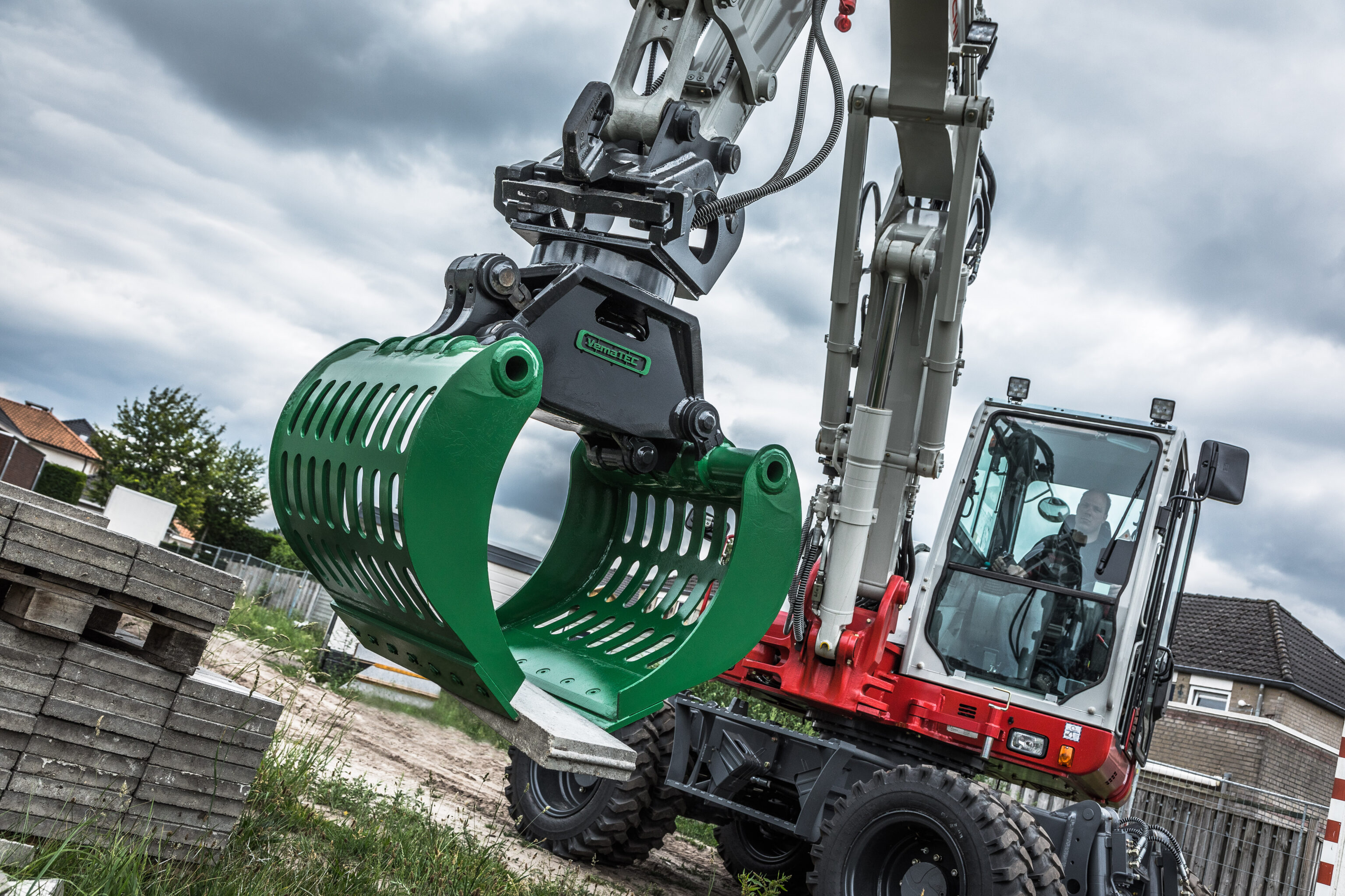 Takeuchi graafmachine die een opsluitband verplaatst met een sorteergrijper
