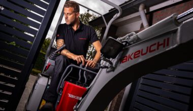 Minigraver rijdt door een smalle poort