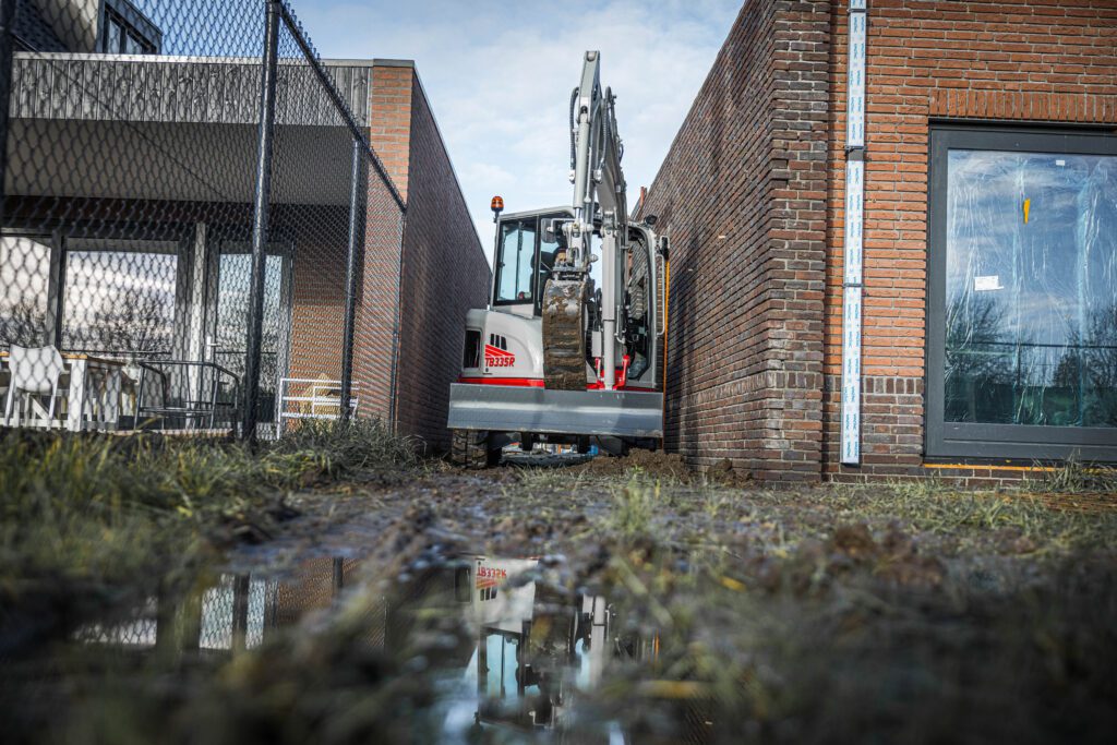 Takeuchi TB335R in smalle tuin tussen 2 gebouwen