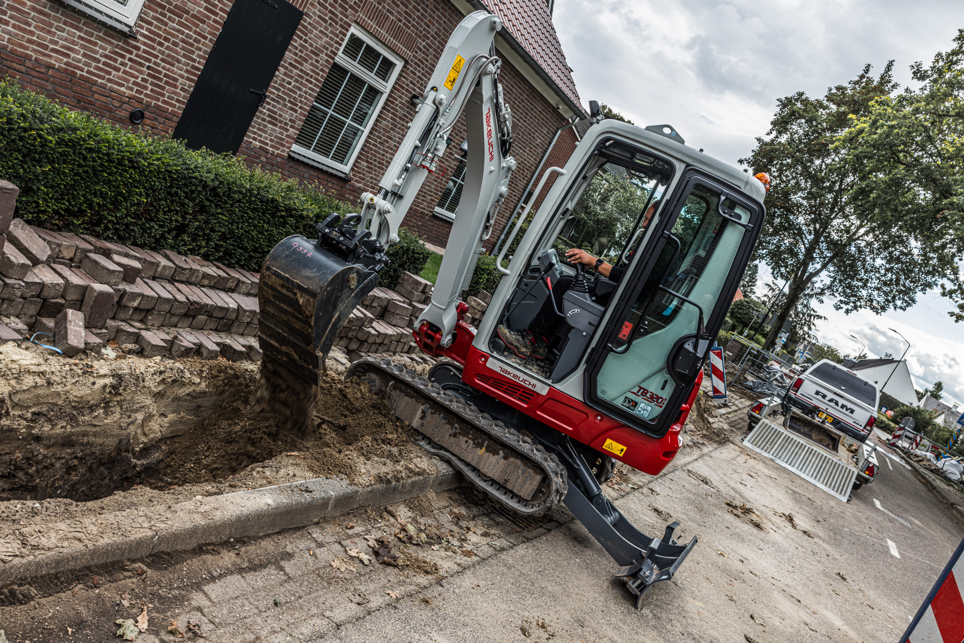 Takeuchi minigraver graaft een sleuf voor bekabeling met een sleuvenbak