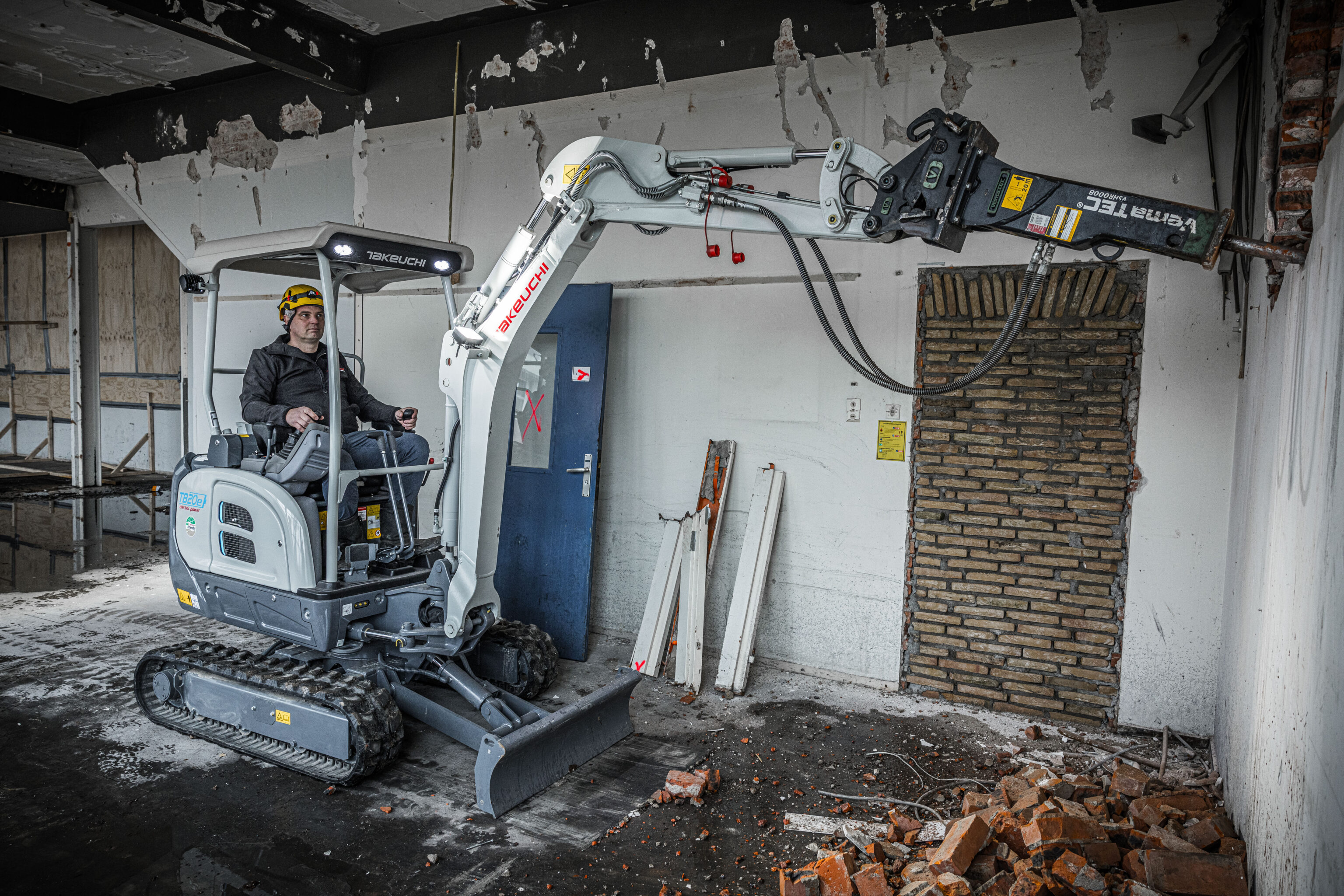 Takeuchi graafmachine sloopt een muur met een hydraulische breekhamer