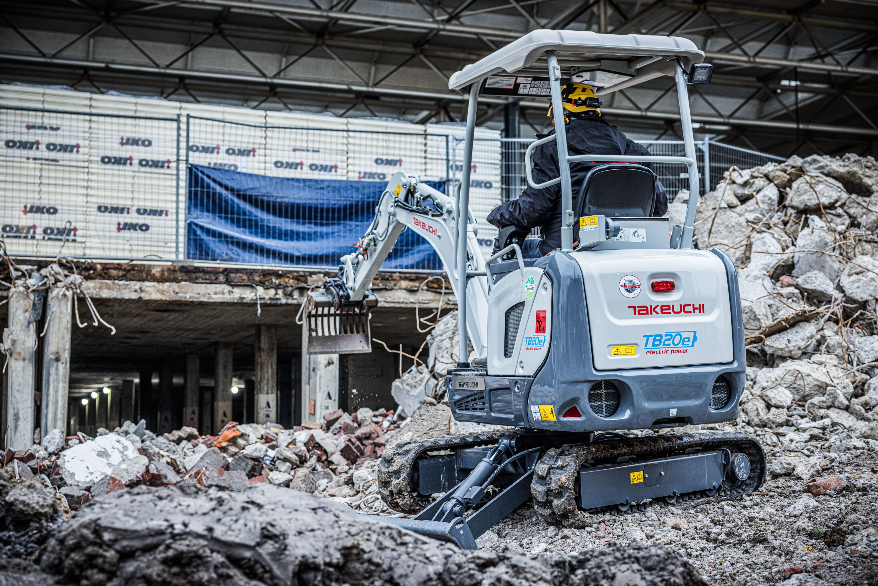 Een Takeuchi elektrisch mini graver is puin aan het sorteren