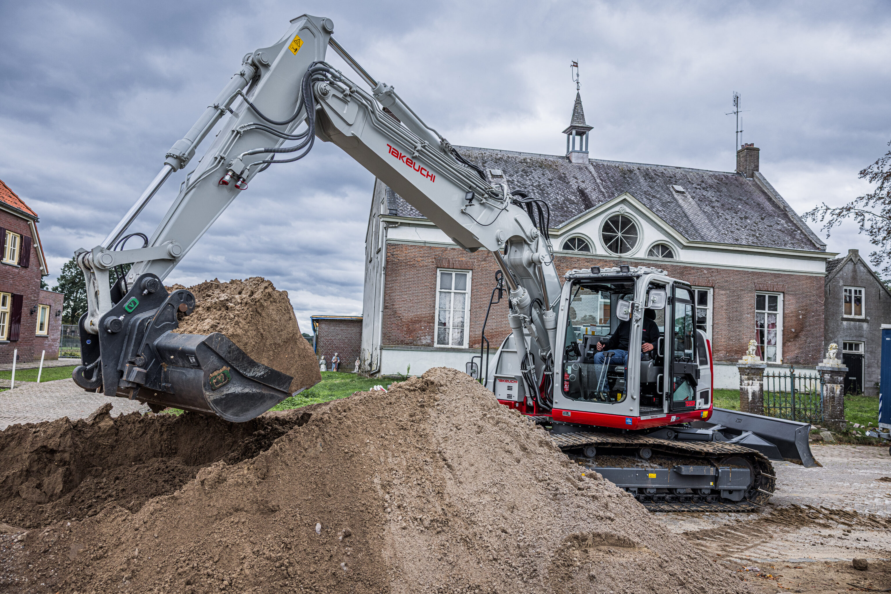 Takeuchi TB3150R verplaatst een hoop zand